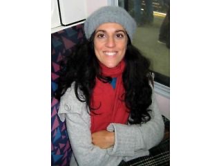 Elvira smiling, in a red scarf and grey hat